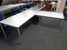 A contemporary twin section corner desk on tubular metal legs,