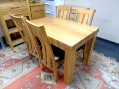 A contemporary oak dining table together with a set of four high backed chairs,