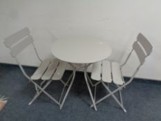 A circular metal bistro style table together with two matching folding chairs