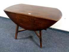 An Ercol solid elm and beech drop leaf table and four Ercol rail back dining chairs