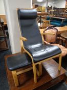 A beech high back armchair in black leather and similar footstool