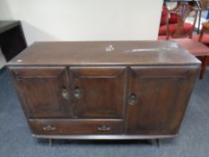 An Ercol solid elm and beech triple door sideboard fitted a drawer in an antique finish