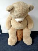 An oversized teddy bear together with a wicker laundry basket