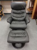 A contemporary black leather swivel adjustable armchair with stool