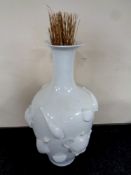 A large glazed ceramic embossed vase depicting tea cups and coffee pots with dried grass,