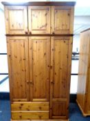 A contemporary pine triple door wardrobe fitted with two drawers with top boxes