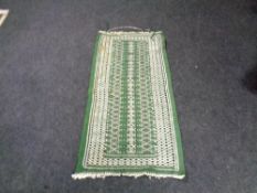 A fringed eastern rug on green ground