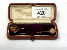 An antique yellow metal coral-set stick pin, together with further yellow metal stick pin.