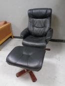 A Scandinavian beech framed swivel armchair upholstered in black leather with similar footstool