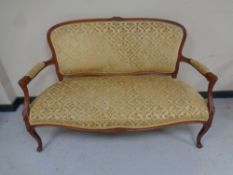 A carved beech framed French salon settee upholstered in a gold brocade fabric