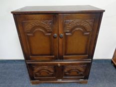 A carved oak double door television cabinet