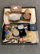 A box containing Russian medals and badges, a silver cup holder,