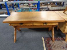 A blonde oak two drawer library table on X frame legs