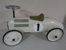 A child's tin ride on car in the form of an early 20th century racing car