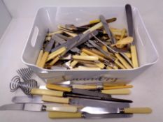 A basket containing a large quantity of stainless steel resin handled cutlery