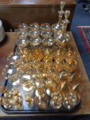 A pair of amber glass liqueur decanters together with a suite of glasses bearing dragon emblem,