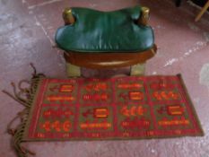 A camel stool with leather saddle together with a fringed hearth rug
