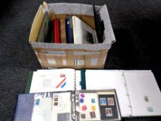 A box containing eleven folders and books containing world stamps and first day covers