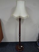 A carved beechwood standard lamp with tasselled shade