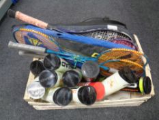 A box containing a quantity of badminton and tennis rackets together with a large quantity of