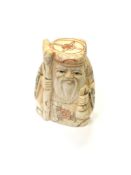 A Japanese carved bone netsuke - Village elder holding a staff.