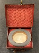 A vintage brown leather fitted top hat carrier, with quilted red fabric lining,