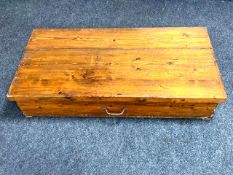 An early twentieth century pine storage box with hinged lid, width 124 cm, depth 61 cm,