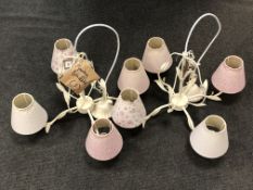 A pair of ornate cream-finish metal four-way light fittings, with shades.