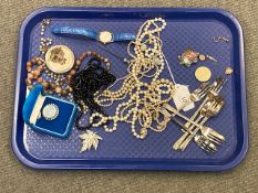 A collection of costume jewellery necklaces, Whitby jet brooch in tin, wrist watch, hat pin,