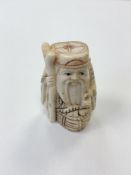 A small Japanese bone carving - Village elder with a basket by his feet.