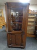A carved oak glazed door corner cabinet