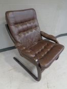 A stained beech framed relaxer armchair upholstered in brown leather