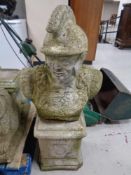 A concrete garden figure of a classical warrior on plinth.
