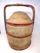 An early twentieth century Chinese wicker lidded two tier hand basket containing sewing items