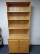 A set of open bookshelves fitted with double door cupboard below in oak finish