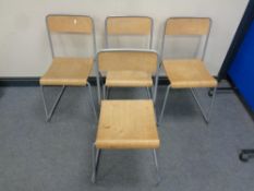 A set of four plywood and tubular metal stacking dining chairs