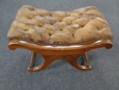 A brown buttoned leather upholstered footstool on X-frame support