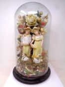 A 19th century glass dome containing two continental bisque figures and foliage.
