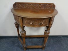 An early 20th century carved oak D-shaped hall table fitted a drawer