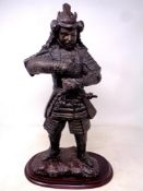 A metal patinated figure of a samurai on wooden base (lacks sword)