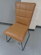 A contemporary brown leather dining chair on metal legs