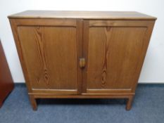 A pine double door cupboard on raised legs with fitted interior