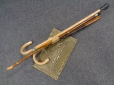 A bundle of assorted walking sticks, military swagger stick together with a brass embossed plaque.