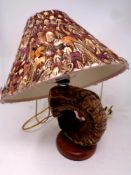 A ram's horn table lamp on a circular wooden base together with a bird feather shade