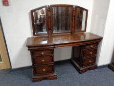 A mahogany effect bow fronted six drawer dressing table with triple mirror back