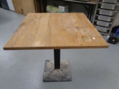 A cast iron based wooden topped square cafe table, diameter 76 cm.