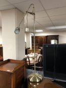 An adjustable standard reading lamp, in antique brass effect finish.