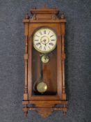 An Edwardian carved oak eight day wall clock with pendulum