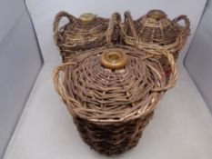 Three glazed stoneware bottles encased in wicker carriers