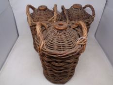 Three glazed stoneware bottles encased in wicker carriers